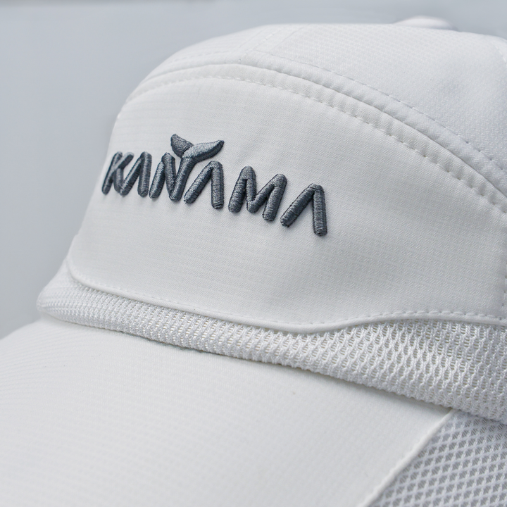 Close-up of white Kanama fishing sun hat with mesh panels and embroidered logo.