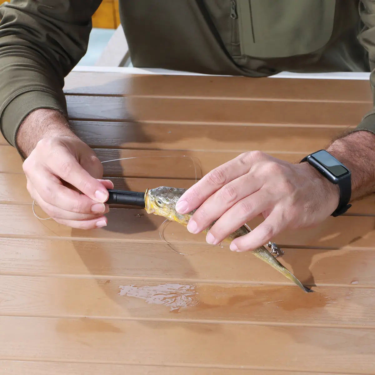 Person applying a yellow substance to a wooden surface with Kanama Smart Bait.