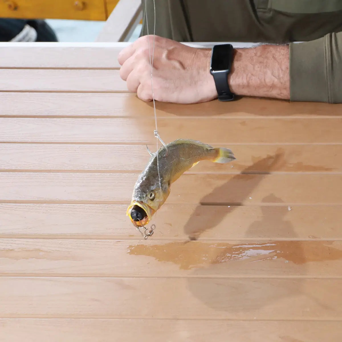 Fishing lure on a hook held over a wooden surface