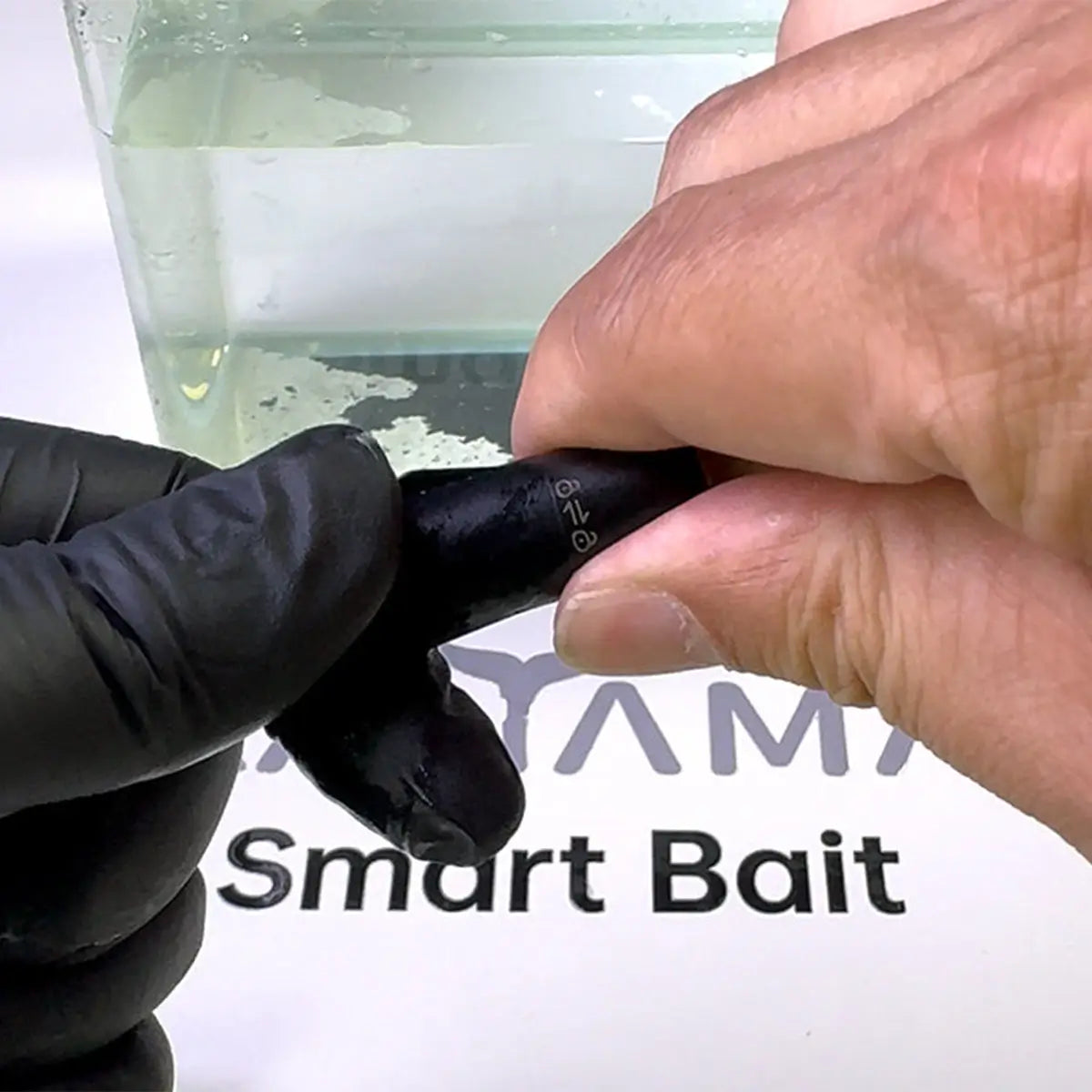 Hand holding a kanama smart bait with a transparent container