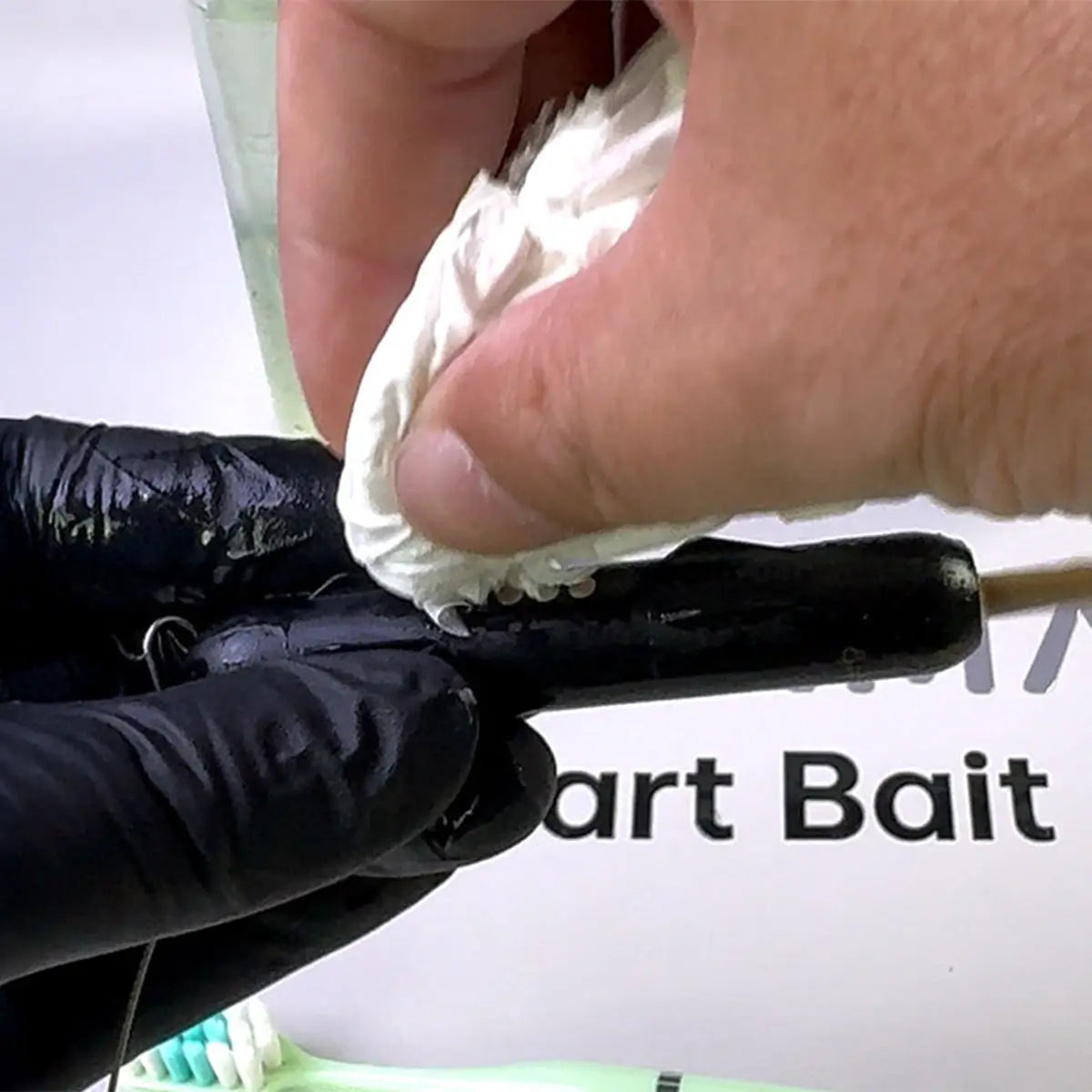 Person applying white substance to a smart bait with a blurred background